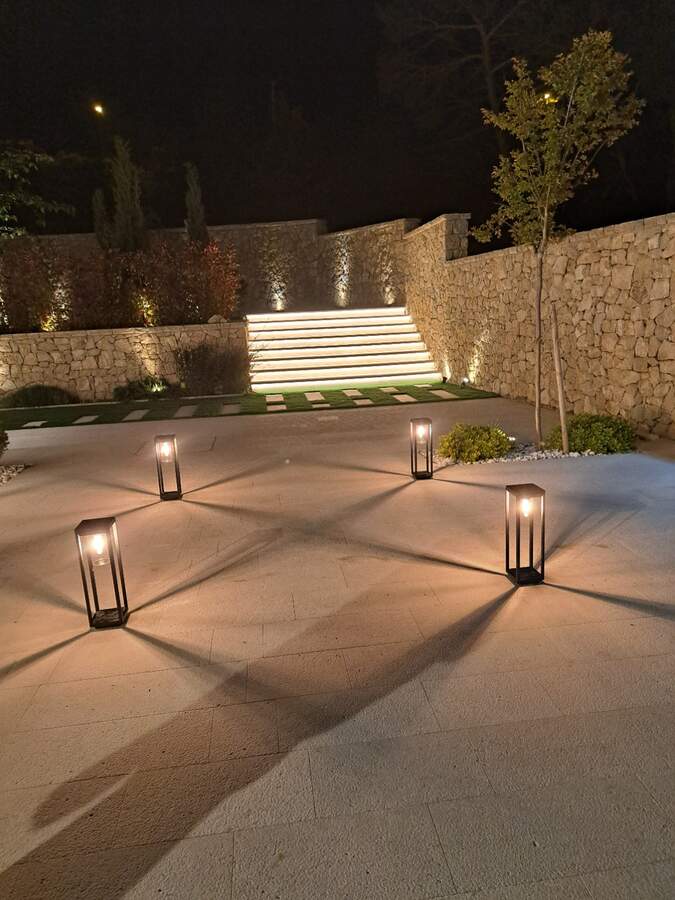 Beleuchtete Außentreppe und Gartenmauer bei Nacht